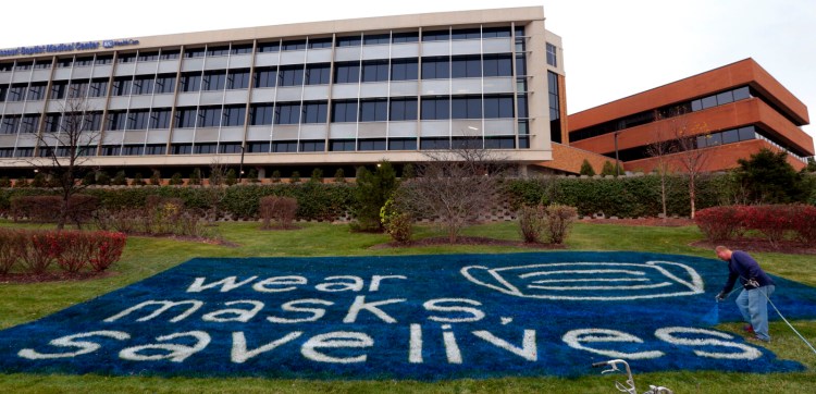 Scott Parker, of Parker Field Design, paints a mask wearing message from Missouri Baptist Medical Center, on the north side of their complex on Friday, Nov. 20, 2020, near St. Louis. (Robert Cohen/St. Louis Post-Dispatch via AP)