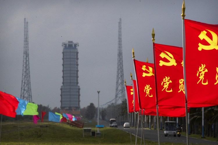 Flags with the logo of the Communist Party of China fly in the breeze near a launch pad in Wenchang on Monday.

