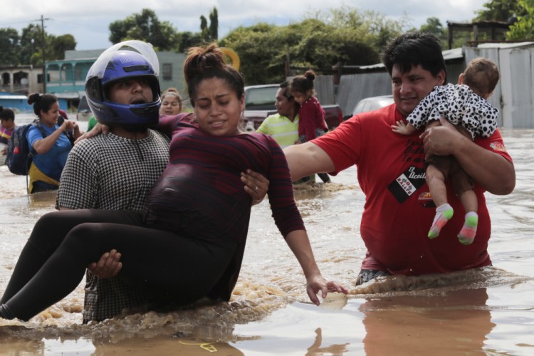 A pregnant woman is carried out of an area flooded by water brought by Hurricane Eta in Planeta, Honduras, on Thursday. The storm that hit Nicaragua as a Category 4 hurricane on Tuesday had become more of a vast tropical rainstorm, but it was advancing so slowly and dumping so much rain that much of Central America remained on high alert.