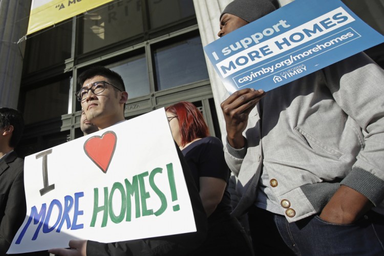 Men hold up signs at a rally outside of City Hall in Oakland, Calif., in January 2020. The Biden administration is expected to embrace policies aimed at stemming evictions and stabilizing housing for renters.