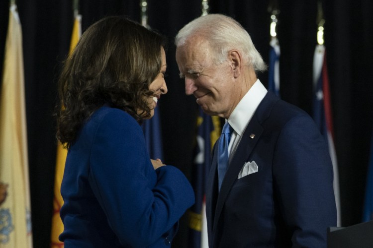 President-elect Joe Biden and his running mate Sen. Kamala Harris, D-Calif., pass each other as Harris moves to the podium to speak. 