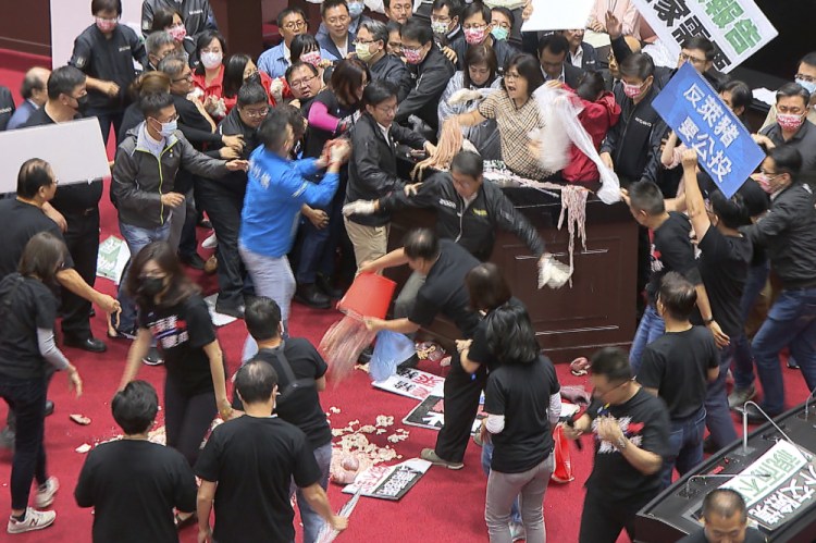 Lawmakers fight during a parliament session in Taipei, Taiwan, Friday , over a soon-to-be-enacted policy that would allow imports of U.S. pork and beef. A blue banner at right reads: “Protest against ractopamine pork, We want a referendum.” (FTV via AP)