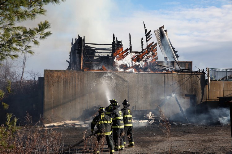 Firefighters extinguish a blaze in a structure that houses a trash compactor at the Peaks Island transfer station on Friday. 