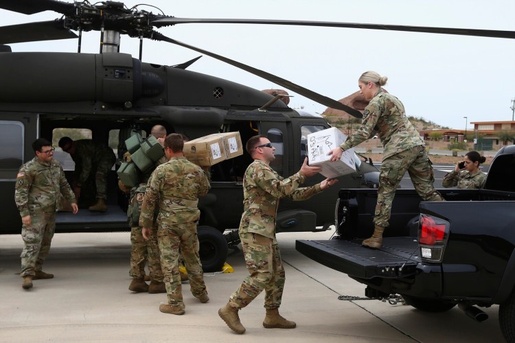 Members of an Arizona National Guard load a helicopter with medical supplies to be taken to the remote Navajo Nation town of Kayenta in April. Tribal members are working to protect elders by delivering meals and protective gear so they can remain safe at home. 