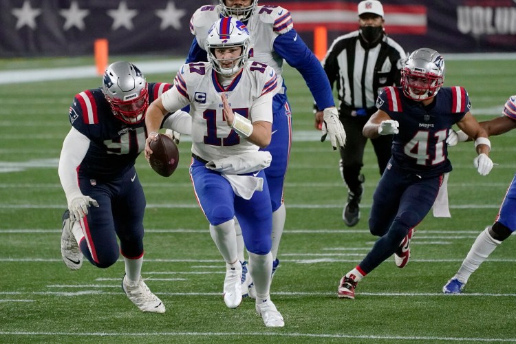 Quarterback Josh Allen, center, runs from New England Patriots defenders Deatrich Wise Jr., left, and Myles Bryant, right, during a Dec. 28  game in Foxborough, Mass.