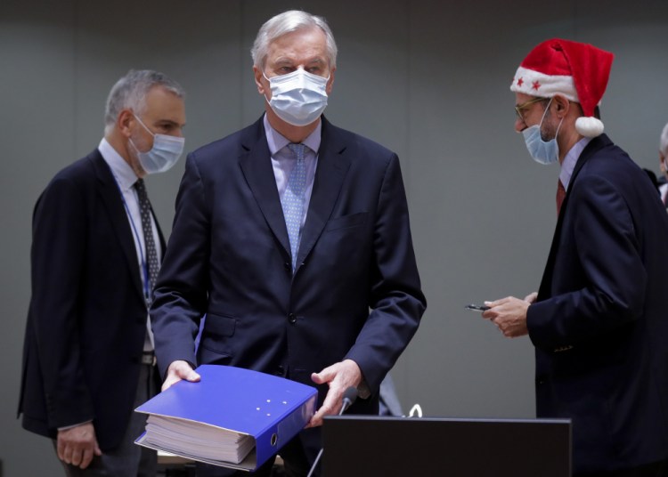 European Union chief negotiator Michel Barnier, center, carries a binder of the Brexit trade deal during a special meeting of Coreper at the European Council building in Brussels on Friday. After the deal was announced on Thursday, EU nations already showed support for the outcome and it was expected that they would unanimously back the agreement, a prerequisite for its legal approval. 