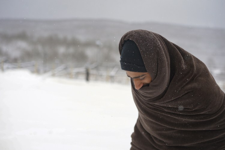 A migrant walks through the snow wrapped in a blanket at the Lipa camp in northwestern Bosnia, near the border with Croatia, on Saturday. (AP Photo/Kemal Softic)