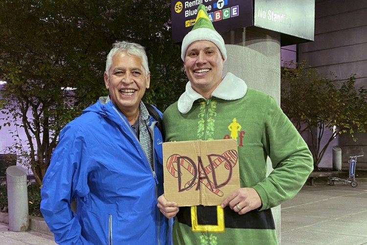 Doug Henning, right, who was adopted as a baby, poses with his biological father after meeting face to face for the first time on Nov. 24 at Logan International Airport in Boston. Henning, of Eliot, Maine, wore a costume like the one actor Will Ferrell's character wore in the movie "Elf" and he broke into the same awkward song from the movie while meeting his father.