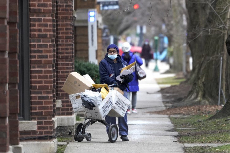 A postal worker delivers packages, boxes and letters Tuesday along her route in the Hyde Park neighborhood of Chicago. 