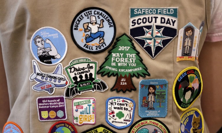 Patches cover the back of a Girl Scout's vest at a demonstration of some of their activities in Seattle in 2018. Girl Scouts of the United States of America claim the century-old organization is in a "highly damaging" recruitment war with Boy Scouts of America after the group opened its core services to girls. (AP Photo/Elaine Thompson, File)