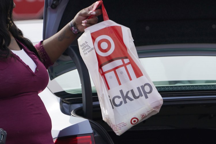 A Target employee places a curbside pickup purchase into the trunk of a customer's car in Jackson, Miss. Many struggling retailers are stepping up discounts while heavily promoting curbside pickup as a way to get shoppers, worried about being infected with  the virus,  to visit their stores.  (AP Photo/Rogelio V. Solis)