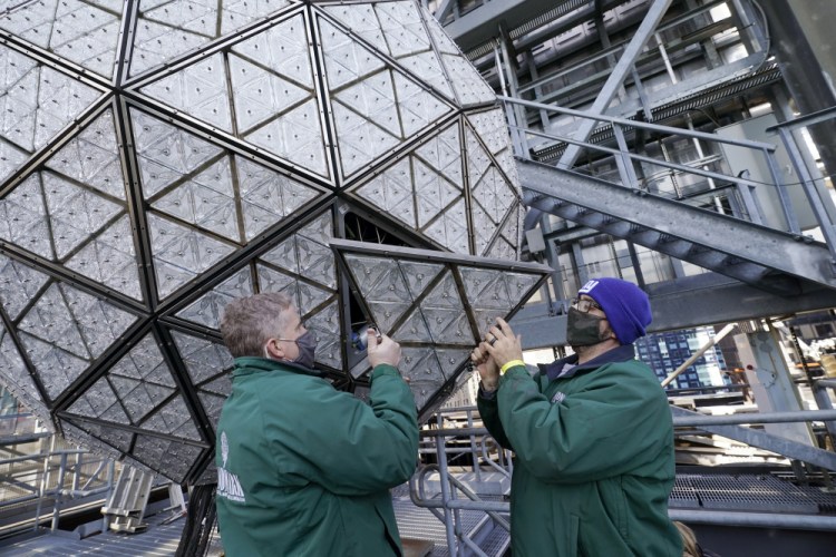 Workers install a panel of Waterford crystal triangles on the Times Square New Year's Eve ball, Sunday in New York, in preparation for a pandemic-limited celebration.