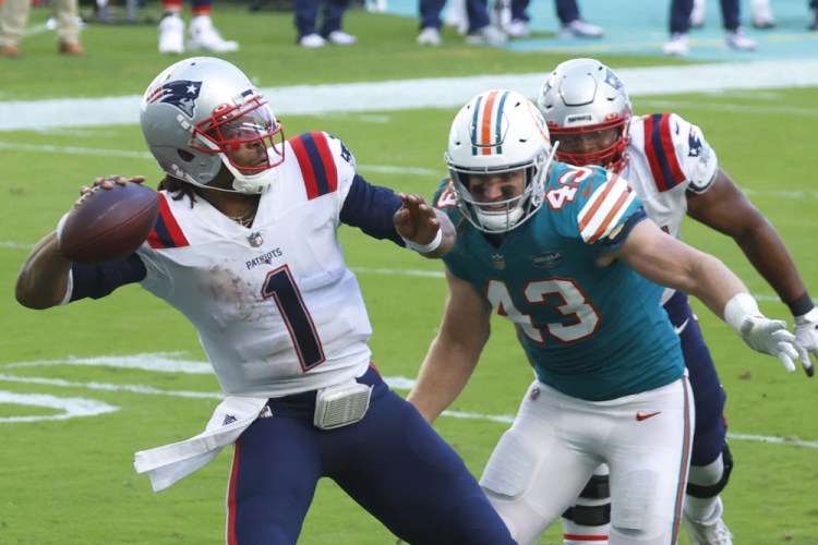 New England Patriots quarterback Cam Newton aims a pass as Miami Dolphins outside linebacker Andrew Van Ginkel attempts to defend during the second half Sunday in Miami Gardens, Fla. 

