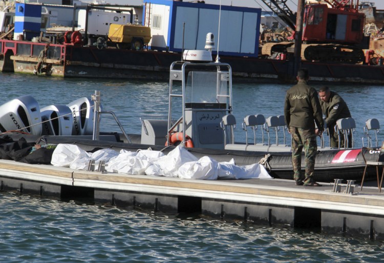 Tunisian coast guards stand next to the bodies of migrants in the port of Sfax on Thursday.


