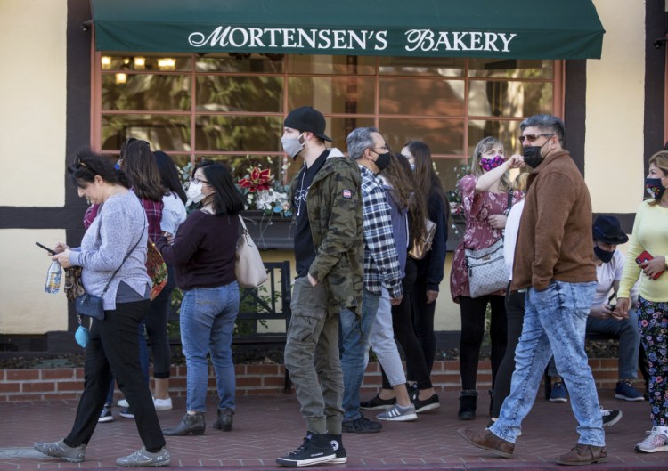 Groups of people, some wearing masks, take over the sidewalks downtown in Solvang, California, on Nov. 28. A new City Council has taken over and told everyone to obey the stay-at-home rules to save lives. (George Rose/Santa Ynez Valley Star via AP)