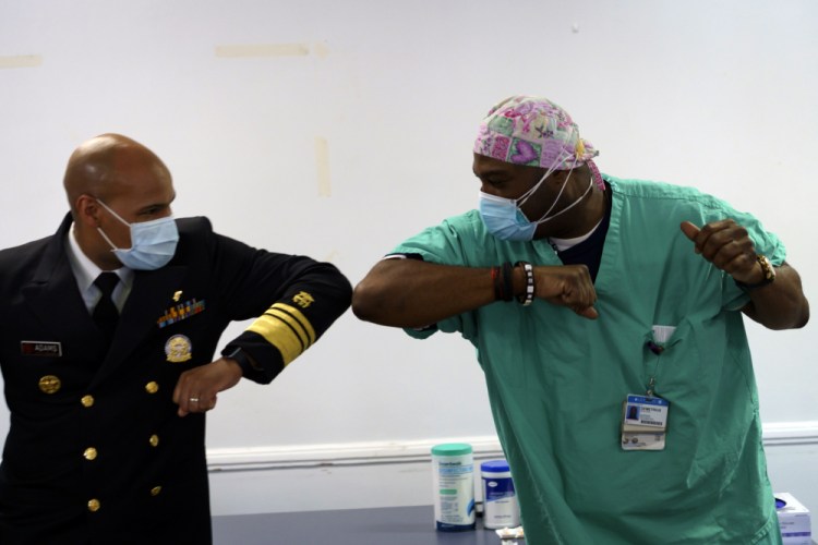 Surgeon General of the U.S. Jerome Adams, left, elbow-bumps Emergency Room technician Demetrius Mcalister after Mcalister got the Pfizer COVID-19 vaccination at Saint Anthony Hospital in Chicago, on Tuesday. 