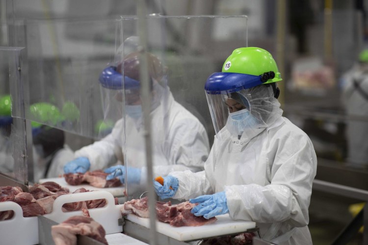 Workers inside Smithfield Foods' pork processing plant in Sioux Falls, South Dakota, wear protective gear and are separated by plastic partitions as they carve up meat in May.