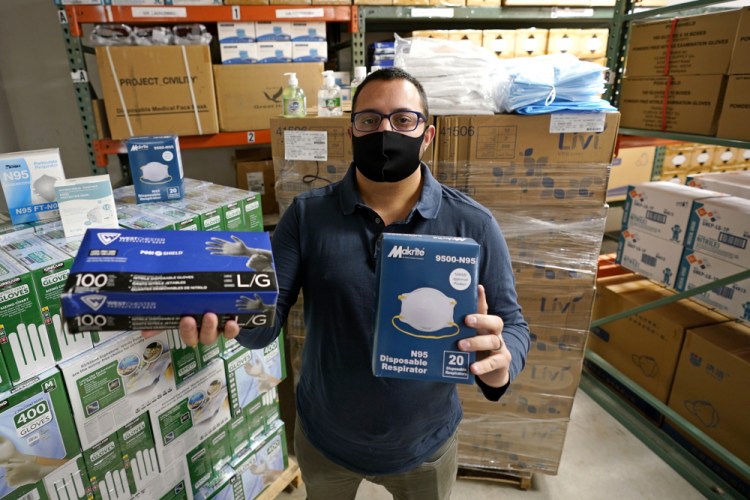 Ray Bellia holds up personal protective masks and gloves, used by medical and law enforcement professionals, in the warehouse of his Body Armor Outlet store in Salem, N.H. Bellia's store rapidly evolved into one of the nation's 20 largest suppliers of personal protective equipment to states this past spring, according to a nationwide analysis of state purchasing data by The Associated Press. (AP Photo/Charles Krupa)