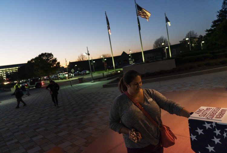 Wendy Gill inserts her absentee ballot at a drop-off box as the sun sets on Election Day outside City Hall in Warren, Mich. (AP Photo/David Goldman)