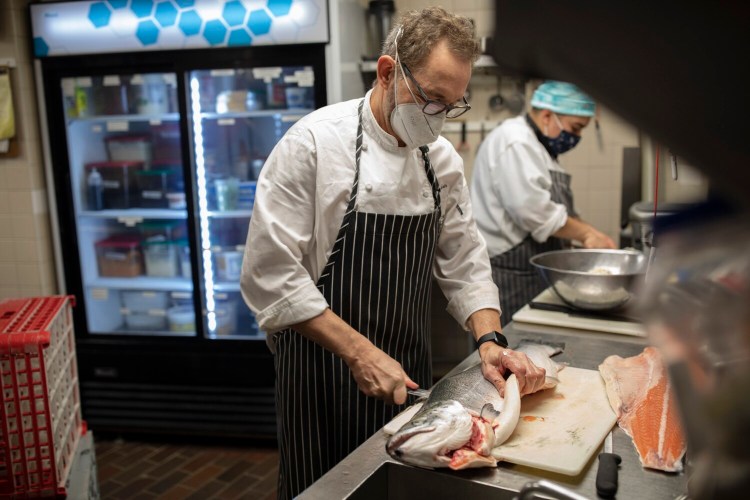 David Turin, chef and owner of David's Restaurants, filets a fish in the kitchen at his restaurant in Monument Square on Jan. 6. Turin has not cut hours or raised prices, but said his restaurants are surviving on government grants.