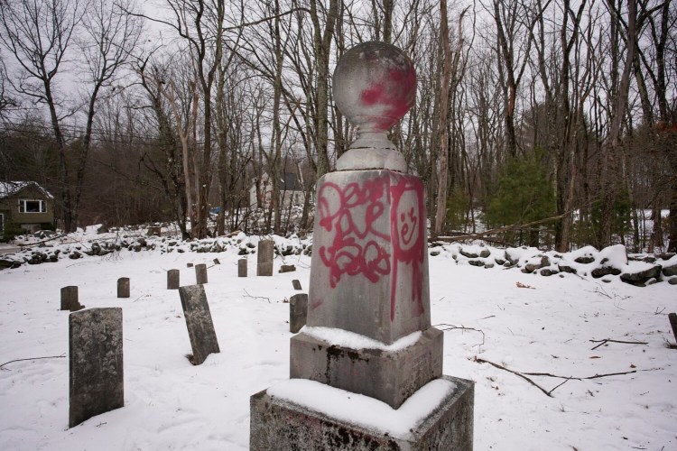Spray painted words and a picture mar a gravestone at the Roberts-Wakefield Cemetery in Waterboro, The York County Sheriff's Office is investigating the vandalism that defaced nearly a dozen grave markers in the historic cemetery. 