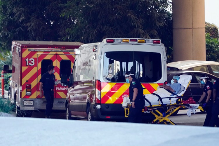 A patient is loaded onto an ambulance outside of the emergency entrance to PIH Health Good Samaritan Hospital on Tuesday in Los Angeles. Ambulance crews have been instructed to use oxygen only for their worst-case COVID-19 patients and not to transport them to the hospital if they have little hope of survival.