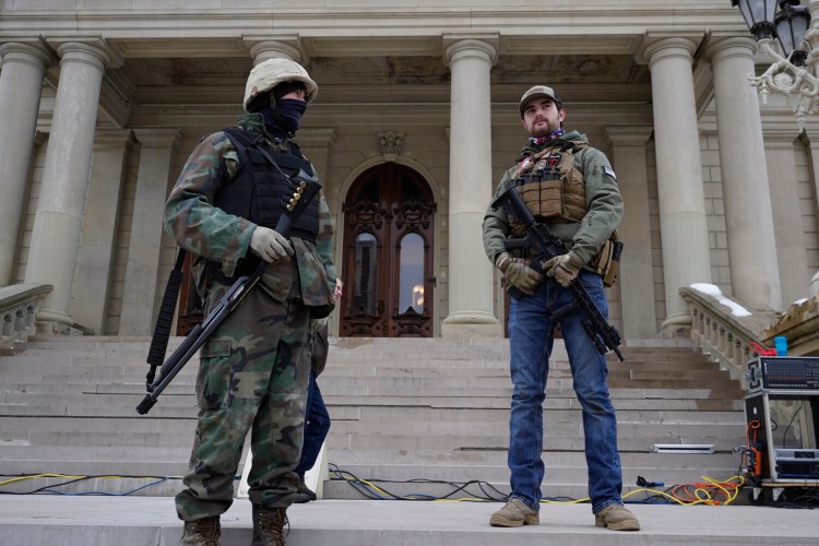 Men with a shotgun and a rifle stand on the steps at the state Capitol after a rally in support of President Trump in Lansing, Mich., on Wednesday.