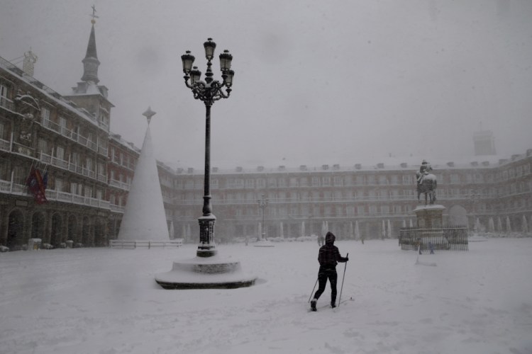 A woman skis while crossing the Plaza Mayor in Madrid during a heavy snowfall Saturday in Madrid, Spain.