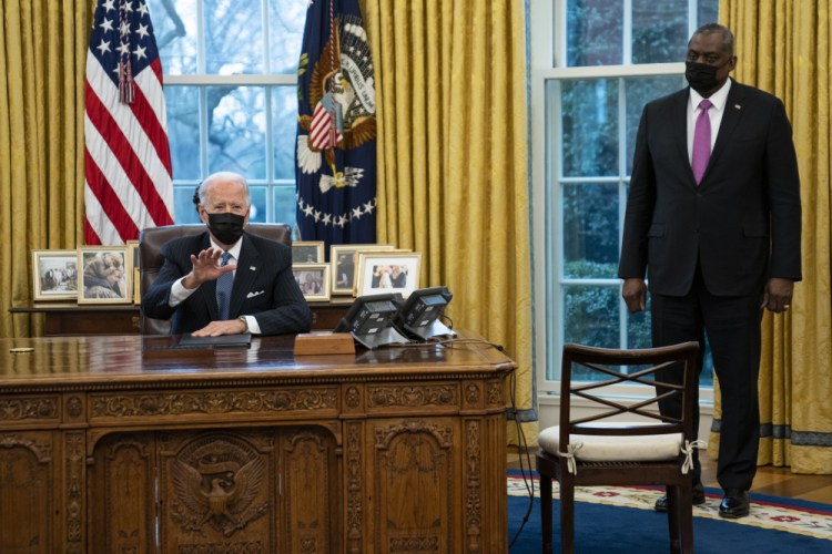 Secretary of Defense Lloyd Austin listens as President Joe Biden speaks before signing an Executive Order reversing the Trump era ban on transgender individuals serving in military, in the Oval Office of the White House, Monday, Jan. 25, in Washington.