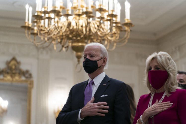 President Biden, accompanied by first lady Jill Biden, places his hand over his heart during a performance of the national anthem, during a virtual Presidential Inaugural Prayer Service in the State Dining Room of the White House on Thursday. 
