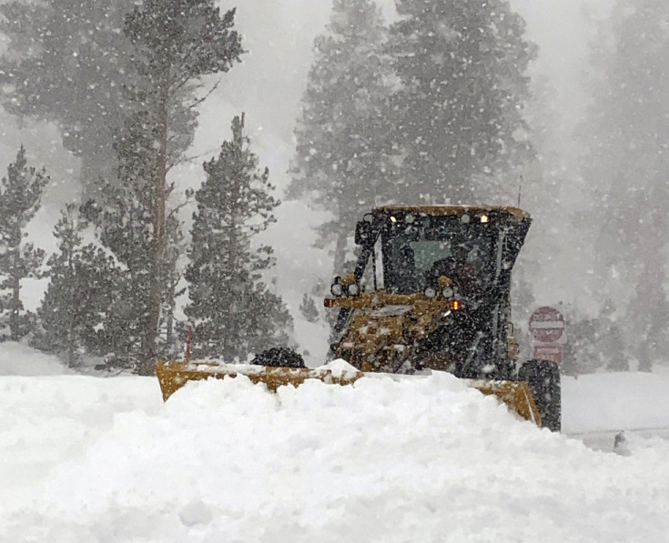 An earth mover clears heavy snow that fell along a closed U.S. Hwy 395 in Mono County, Calif., on Jan. 27 in blizzard conditions that buried the Sierra Nevada in snow. (Greg Miller/Caltrans District 9 via AP)