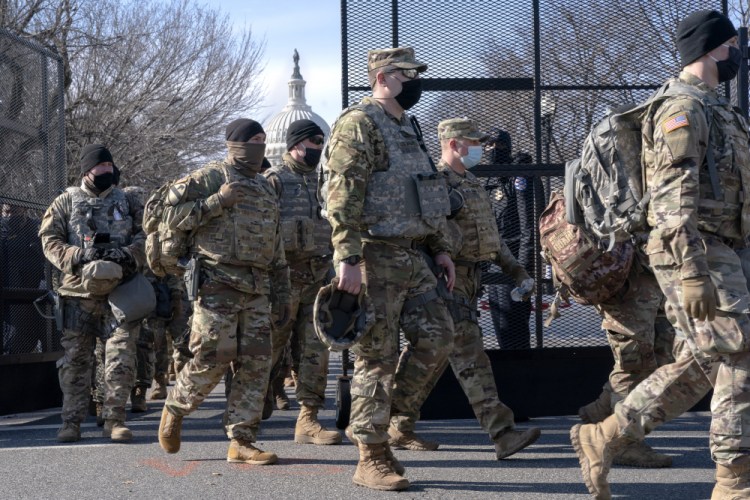 With the U.S. Capitol in the background, members of the National Guard change shifts as they exit through anti-scaling security fencing on Saturday in Washington.

