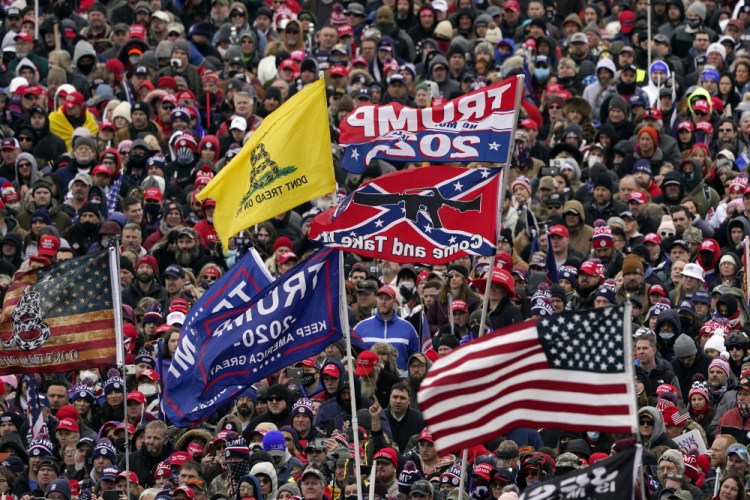 Supporters listen as President Trump speaks Jan. 6 while a Confederate-themed and other flags flutter in the wind during a rally in Washington. 


