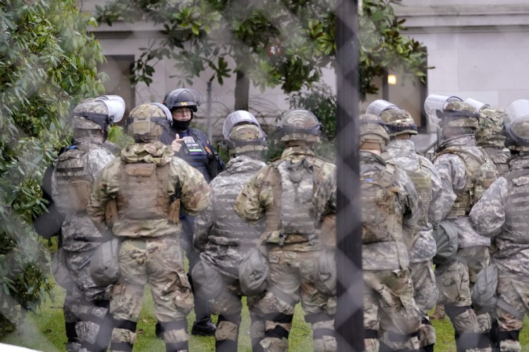 A Washington State Patrol trooper talks with members of the Washington National Guard on Monday outside the state capitol building in Olympia, Wash. State capitols across the country are under heightened security after the siege of the U.S. Capitol last week.