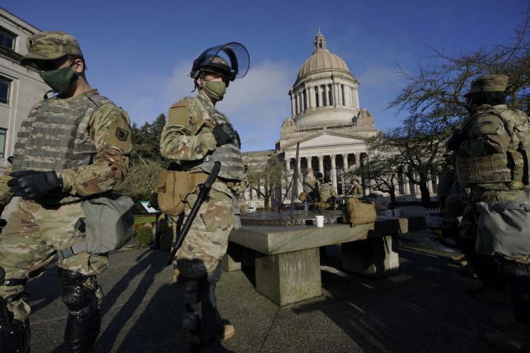 Members of the Washington National Guard stand at a sundial near the Legislative Building, Sunday, at the Capitol in Olympia, Wash. 