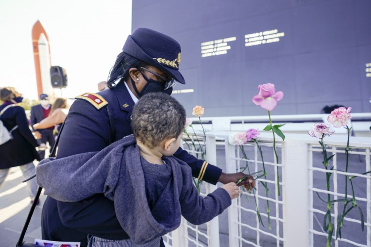 Retired Army Colonel Cynthia Watkins places a flower at the Space Mirror Memorial during a ceremony Thursday to honor fallen astronauts at the Kennedy Space Center Visitors Complex, in Cape Canaveral, Fla.
