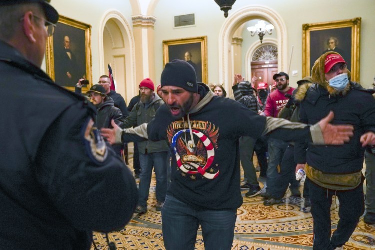 Trump supporters gesture to U.S. Capitol Police in the hallway outside of the Senate chamber at the Capitol in Washington, Wednesday, Jan. 6. 