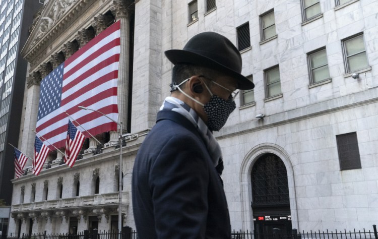 A man passes the New York Stock Exchange. U.S. stocks fell from their record highs on Monday. Rising virus cases, the emergence of a mutant variant and concerns that the rollout of the vaccine isn't happening fast enough are keeping investors on edge, said Adam Taback, chief investment officer for Wells Fargo Private Bank. 