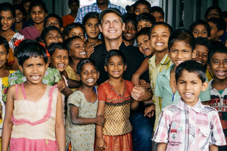 John Marshall looking at the camera surrounded by kids in Visakhapatnam, India.
