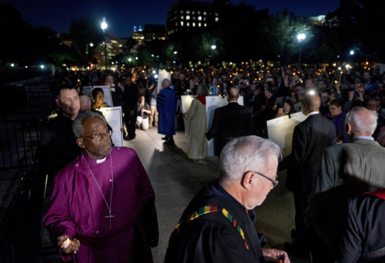 The Most Rev. Michael Curry, left, the presiding bishop of the U.S. Episcopal Church, and others take part in a candlelight vigil outside the White House in Washington in 2018. 


