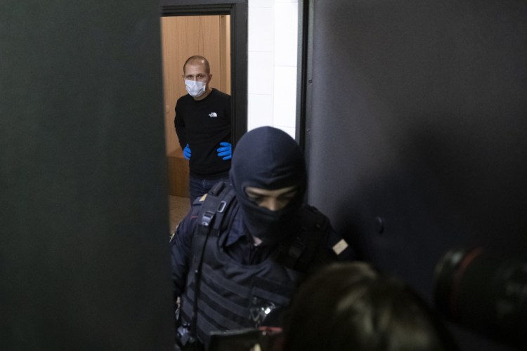 A police officer and an investigator stands behind the door of the apartment of jailed opposition leader Alexei Navalny on Wednesday in Moscow, Russia.