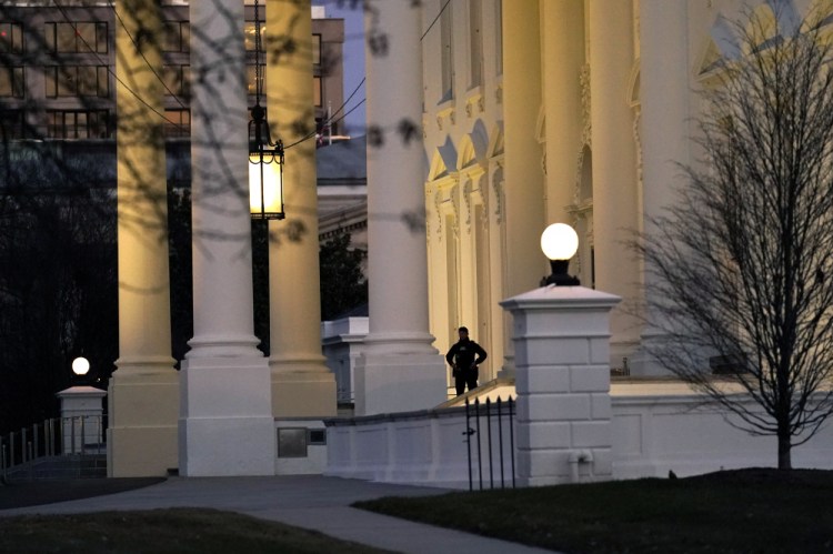 A U.S. Secret Service guard stands at the North Portico of the White House after the U.S. House impeached President Trump in Washington on Wednesday. It isn't clear when Trump will leave the White ouse for good because he isn't adhering to any traditional protocols for the transition of power.