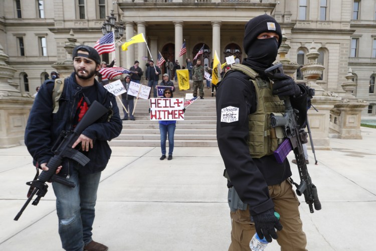 Protesters carry rifles near the steps of the Michigan State Capitol building on April 15 in Lansing, Mich. 