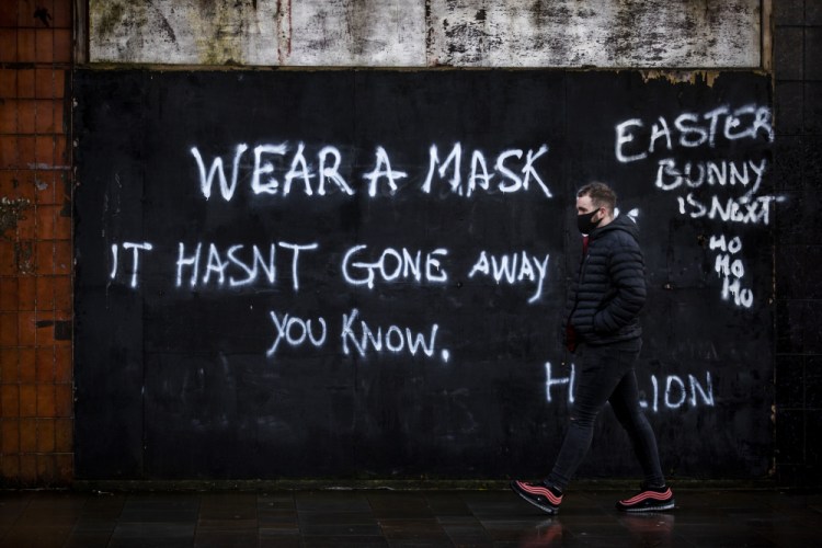 A man walks past graffiti on the Lower Newtownards Road in Belfast on Friday.


