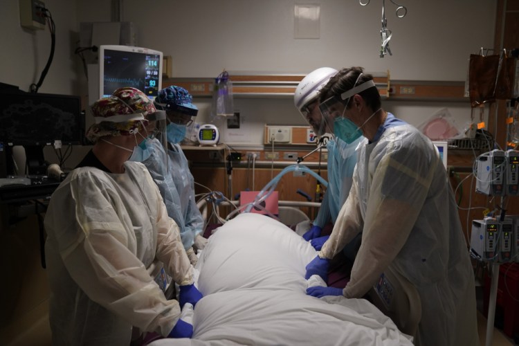 Medical workers prepare to manually prone a COVID-19 patient in an intensive care unit Dec. 22 at Providence Holy Cross Medical Center in the Mission Hills section of Los Angeles.