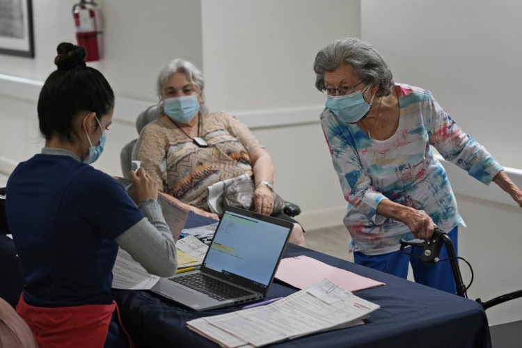Mitzi Hansrote, right, 86, and Deanna Sutton, center, 83, check in before receiving the COVID-19 vaccine on Thursday at the Isles of Vero Beach assisted and independent senior living community in Vero Beach, Fla. 