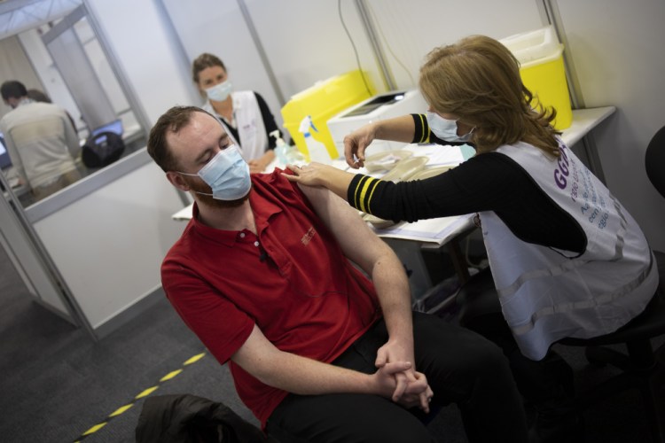 An employee of the Municipal Health Service GGD, right, administers a Pfizer-BioNTech COVID-19 vaccine to a health care worker at a coronavirus vaccination facility in Houten, central Netherlands, last week. Evidence so far suggests that the new mutations will have little, if any, impact on how well the vaccines work, and they do not seem to result in more severe illness.