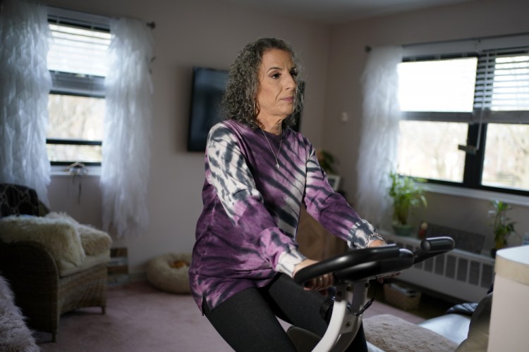 Catherine Busa rides an exercise bike as part of her recovery from COVID-19 at her home in New York. The 54-year-old didn’t have any underlying health problems when she caught the virus in March. Eight months later, she's still battling fatigue, muscle weakness and altered senses. 