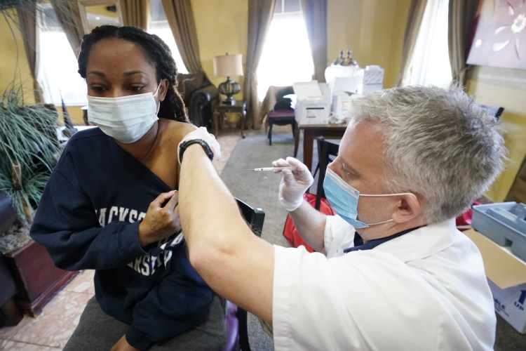 Walgreens pharmacist Chris McLaurin prepares to vaccinate Lakandra McNealy, a Harmony Court Assisted Living employee, with the Pfizer-BioNTech COVID-19 vaccine, on Tuesday in Jackson, Miss. 