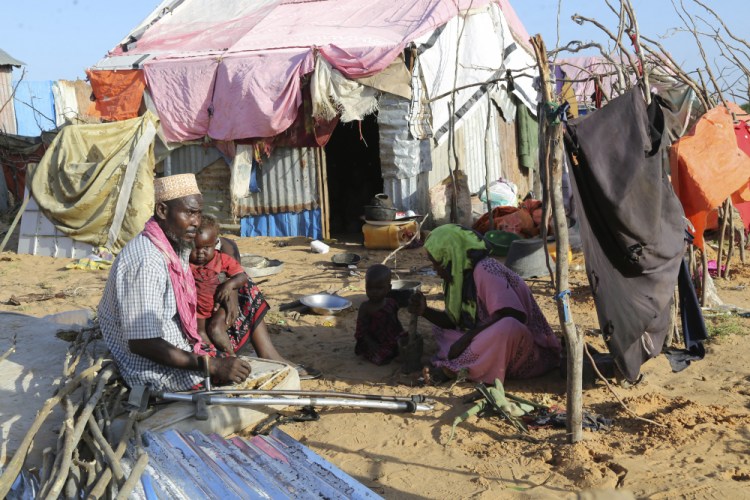 Hassan Mohamed Yusuf, 45, sits with his family at their makeshift shelter at the Dayniile camp in Mogadishu, Somalia on  Dec. 17, 2020. Three of his young children died after having a cough and high fever, but they had no access to coronavirus testing or proper care.